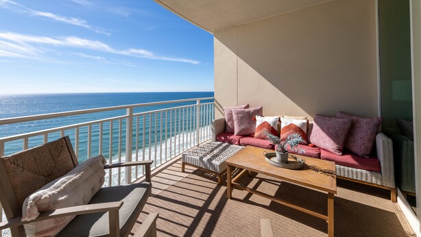Un balcon avec vue sur l’océan, aménagé avec un canapé, une chaise et une table.