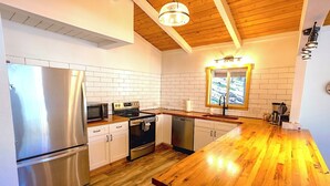 Una cocina moderna con electrodomésticos de acero inoxidable, armarios blancos y una encimera de madera.
