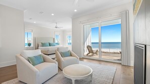 A spacious living room with a large sliding glass door leading to a balcony with a view of the ocean. - Jolie Cote Beach House | Gulf Front | Private Pool | Beach Getaways (Pensacola)