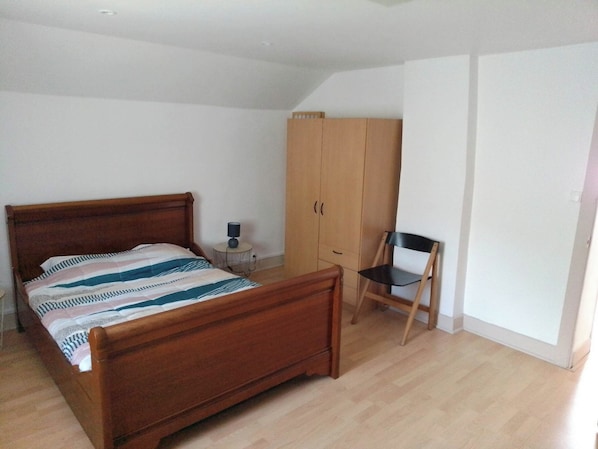 A bedroom with a wooden bed, a wardrobe, a small table with a lamp, and a chair. - LA CHAZOTTE HUT (Bussière-Dunoise)