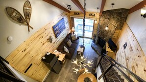 A cozy interior with wooden walls, a stone fireplace, a dining area, and a staircase. - Studio Loft  - Kitchenette, King bed ! (Durango)