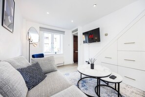 A modern living room with a sofa, coffee table, and a mounted TV displaying the Netflix logo.