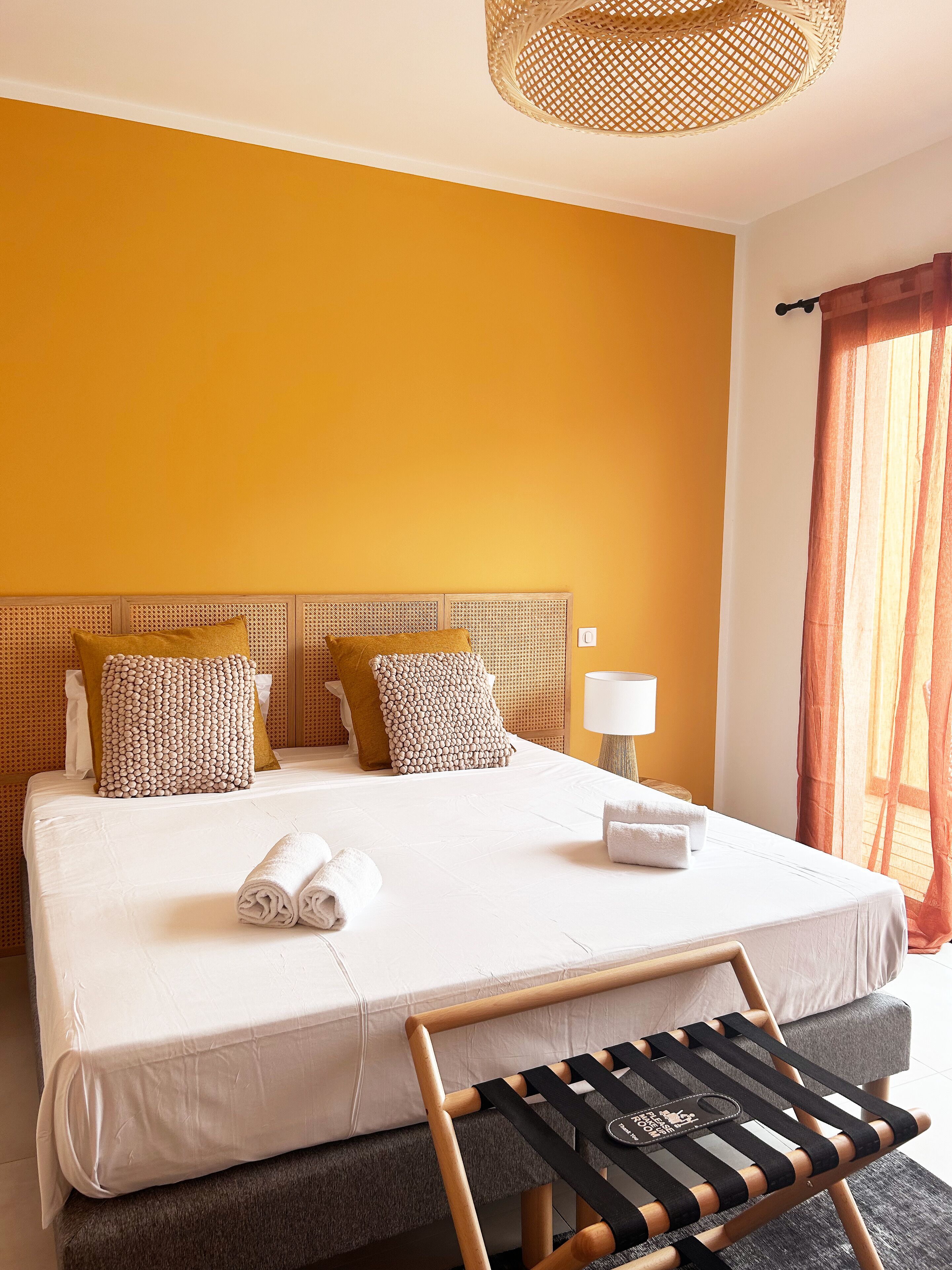 A hotel room with a large bed, a wooden headboard, and a bedside table with a lamp.