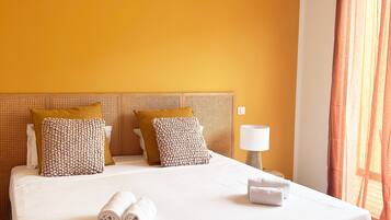 A hotel room with a large bed, a wooden headboard, and a bedside table with a lamp.