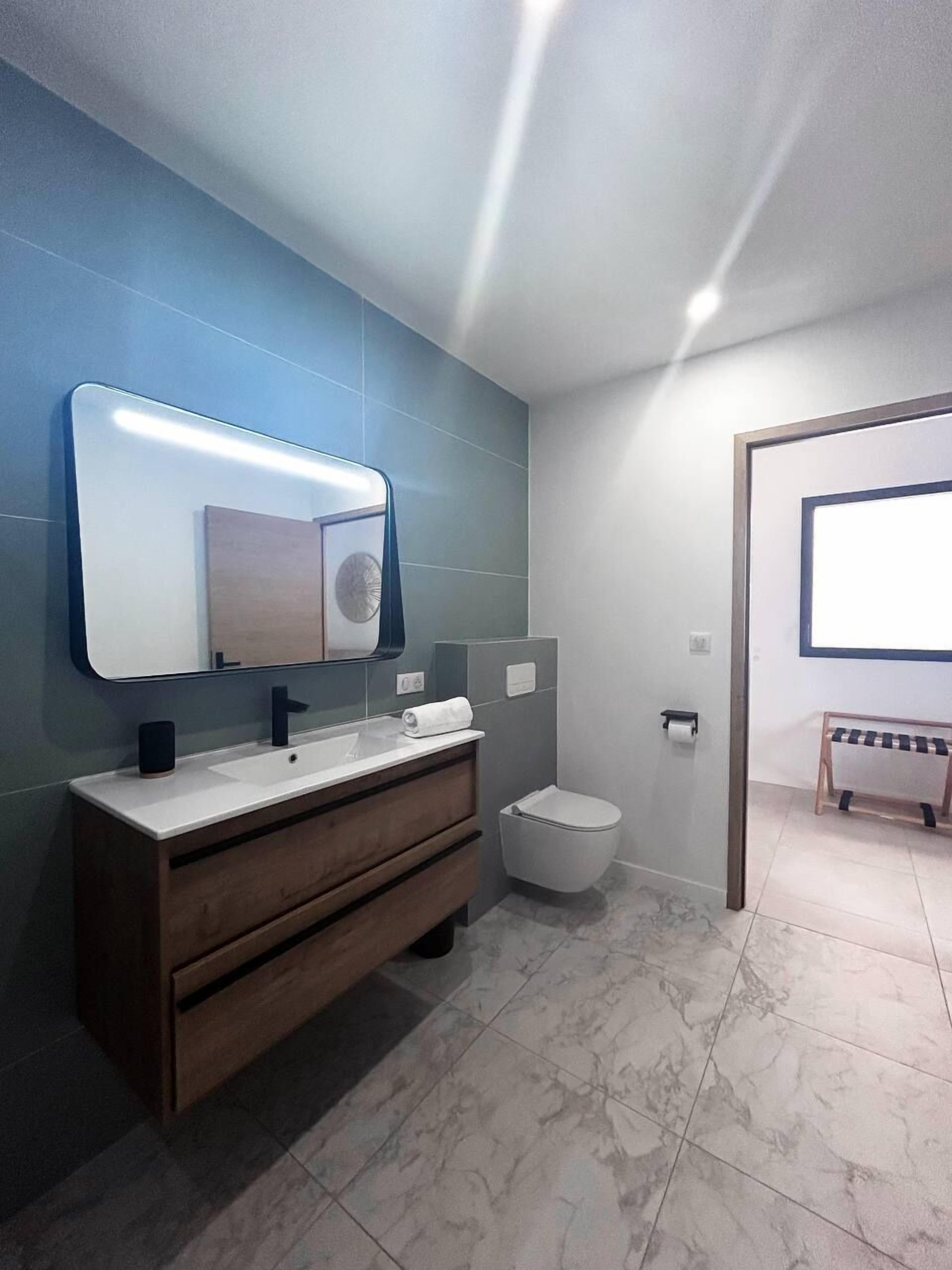 Une salle de bain moderne avec un meuble-lavabo, des toilettes et un grand miroir.