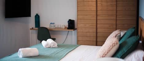Una habitación de hotel con cama, escritorio, silla, televisión y armario.