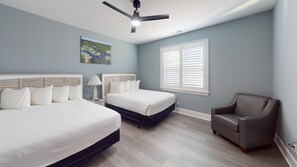 A bedroom with two beds, a ceiling fan, a window with blinds, and a chair. - Saw Mill Sunset Beach, NC (Sunset Beach)