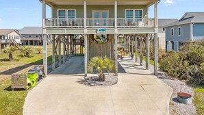 A two-story house with a balcony, a covered walkway, and a sign indicating a beach view. - Toes in the Sand - Ocean Views, Steps from Beach (Oak Island)