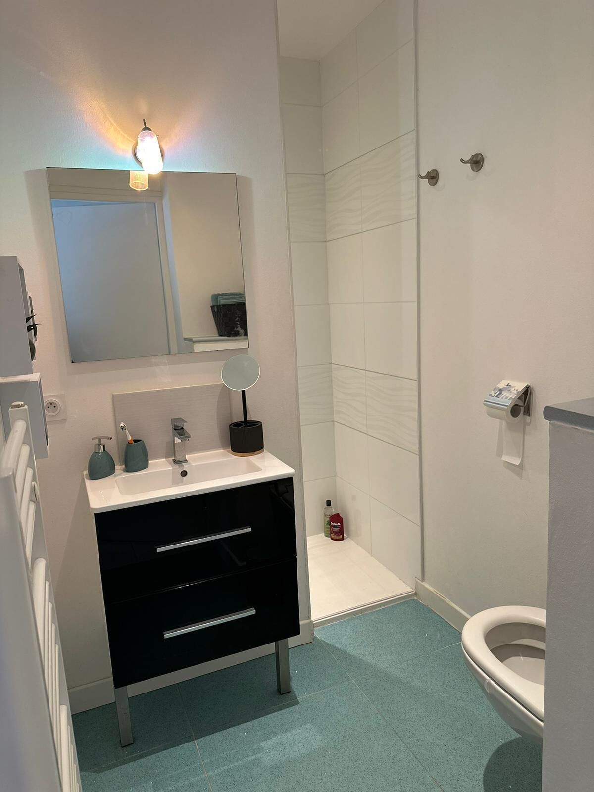 A modern bathroom with a white sink, black vanity, and a toilet.