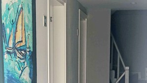 A hallway with patterned flooring, a staircase, and a painting on the wall. - CALİSTO 17 BUTİK OTEL (Bozcaada)