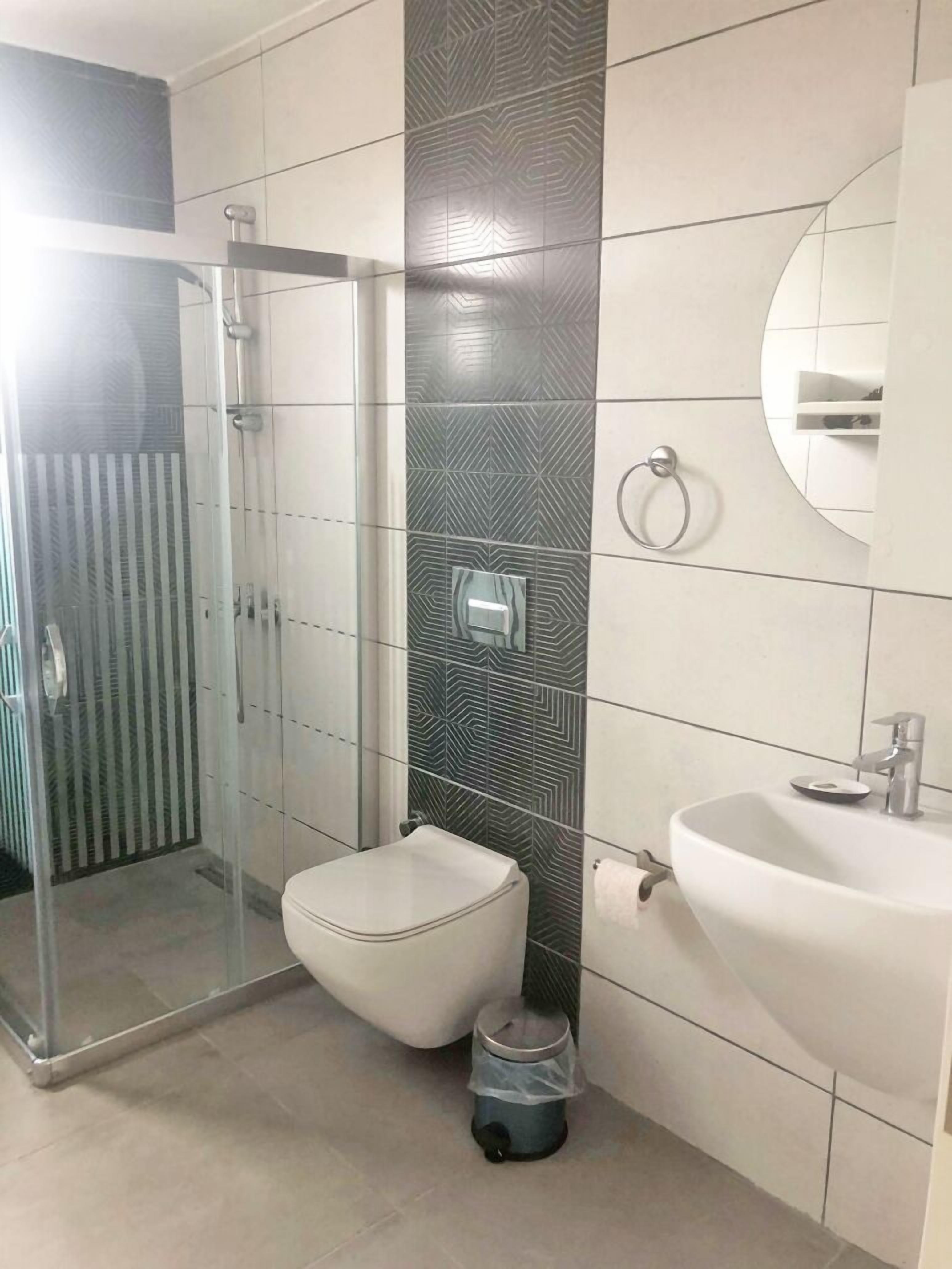 Uma casa de banho moderna com cabine de chuveiro em vidro, sanita e lavatório.