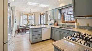 A kitchen with a central island, a gas stove, and light blue cabinets. - Lovely mountain home in a beautiful wooded setting. Welcome to Hart's Horn! (Davis)