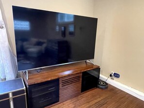 Ein Flachbildfernseher an einem Holzkasten befestigt, ein Kabelanschlussgerät steht auf dem Boden.