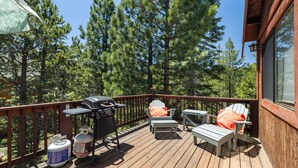 Eine Holzterrasse mit Gartenmöbeln, einem Grill und Propangasflaschen.