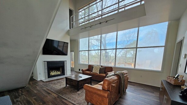 A spacious living room with a fireplace, large windows, and a loft area. - Eureka Springs getaway 2 acres in the center of town, super close to historic DT (Eureka Springs)