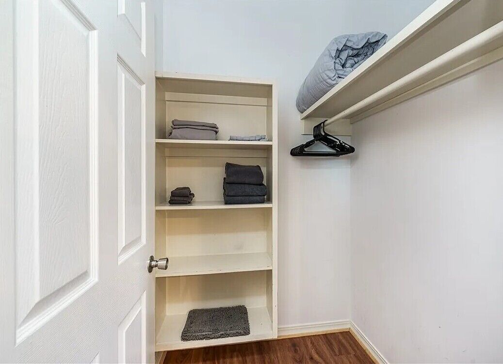Un vestidor con estantes, una barra para colgar ropa y una puerta.
