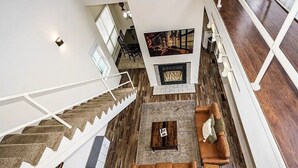 A spacious living area with a fireplace, a staircase, and a large window. - Eureka Springs getaway 2 acres in the center of town, super close to historic DT (Eureka Springs)