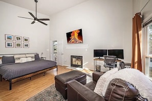 Ein Schlafzimmer mit Bett, Schreibtisch, Stuhl, Kamin und Fernseher.