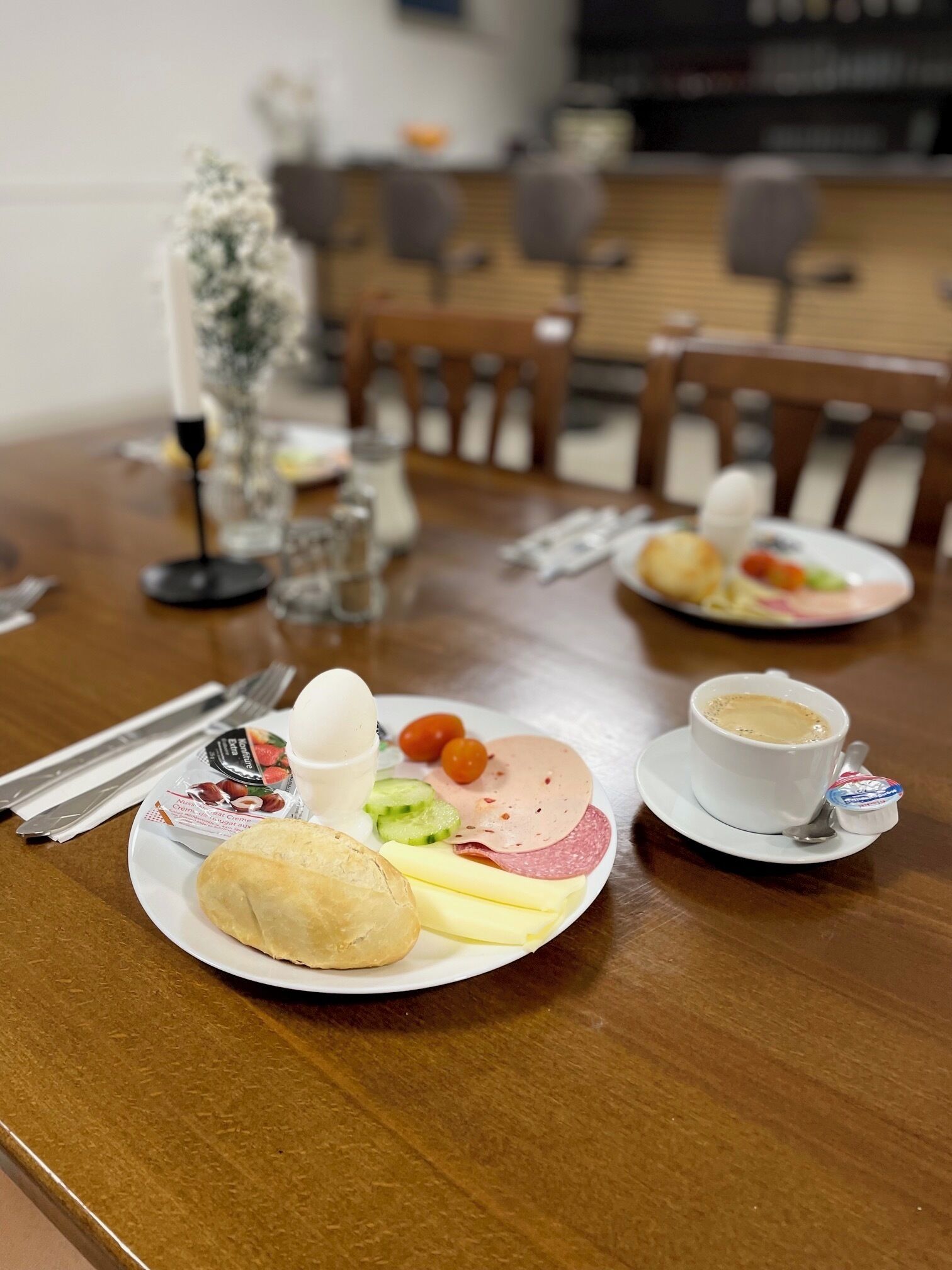 A dining table with plates of food, a cup of coffee, and a small container of yogurt.