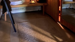 Et sauna-rum med bænk, en flaske og håndklæder.
