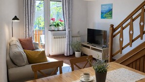 Tunnelmallinen olohuone, jossa on sohva, puinen pöytä, jonka päällä on kirja ja kuppi, televisio ja portaat.