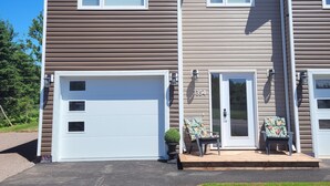 Ein zweistöckiges Wohnhaus mit Garage, überdachter Veranda und kleinem Garten.