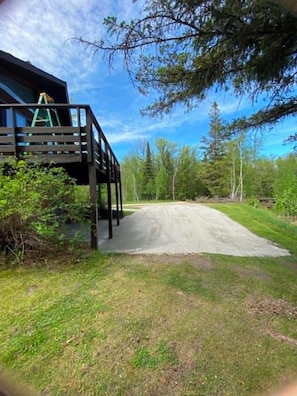 A wooden deck leading to a building with a ladder, surrounded by trees and a clear sky. - Private Riverfront Retreat Near Lake of the Woods. Sleeps 10+ (Warroad)