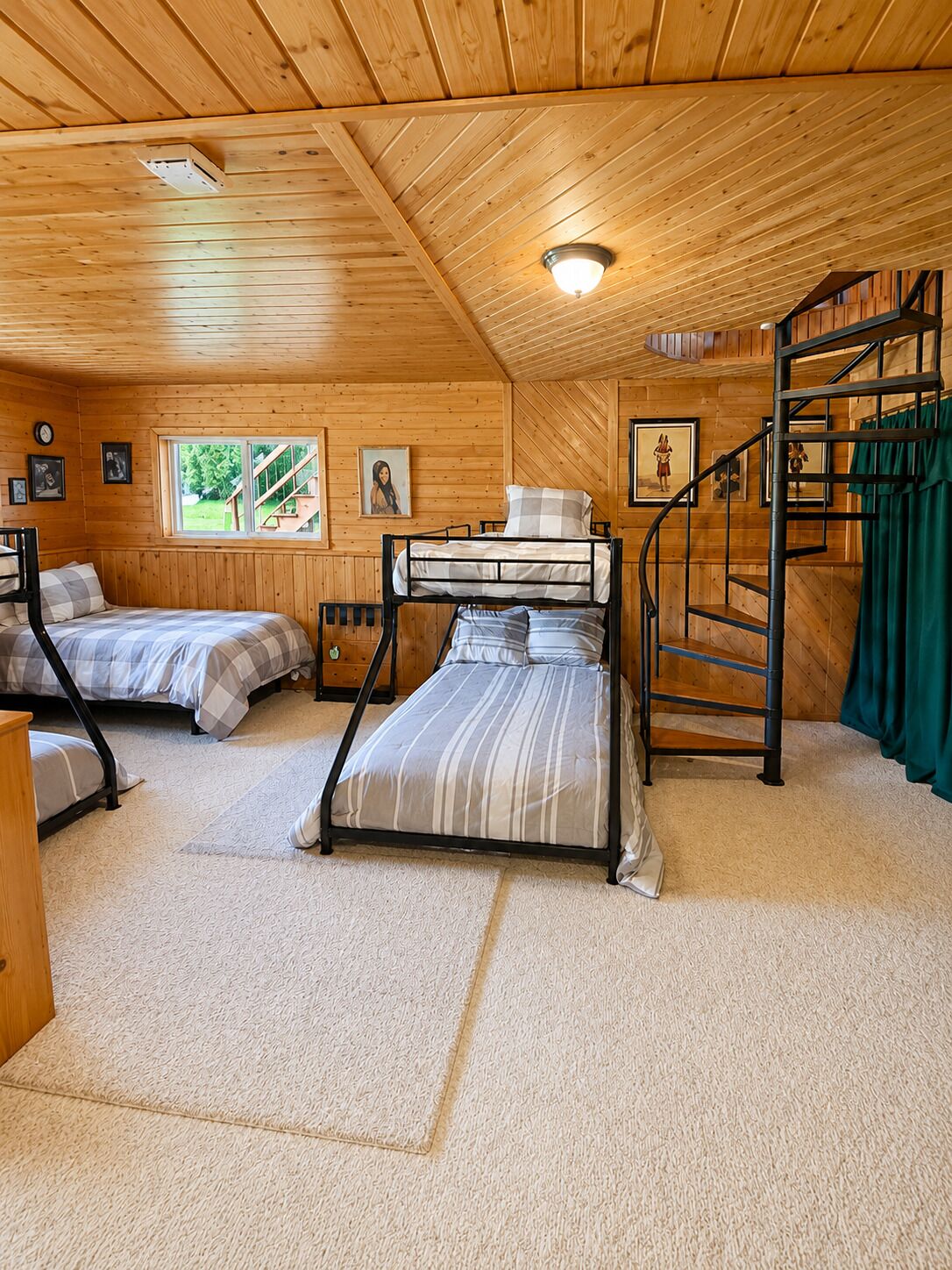 A cabin with two bunk beds, a staircase, and a window with a view of the outdoors.