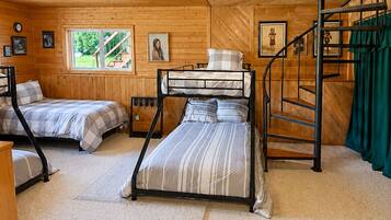 A cabin with two bunk beds, a staircase, and a window with a view of the outdoors.