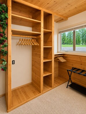 A wooden closet with multiple shelves and a hanging rod, a black drying rack, and a window with a view of trees. - 25% OFF Members. Riverfront. Lake Of the Woods 2mi. Pets Free (Warroad)