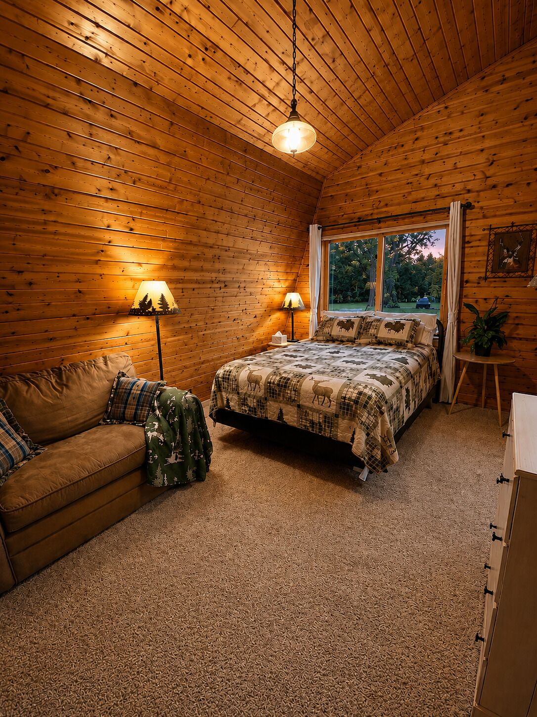 Un dormitorio acogedor con techo de madera, una cama con colcha estampada, un sofá de cuero marrón y dos lámparas de pie.