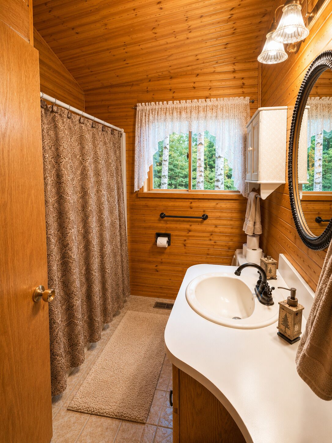 A wooden cabin bathroom with a sink, mirror, and window.
