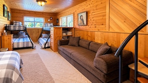 A cozy cabin interior with a bunk bed, a sofa, a desk, and a staircase. - UP TO 25% OFF Members. Riverfront. Lake Of the Woods 2mi. Pets Free (Warroad)