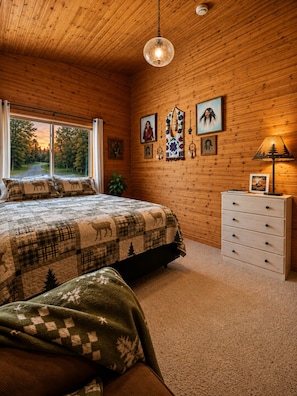 A cozy room with a bed, a dresser, and a window with a view of trees. - Vrbo Members Save 25–27%!. Riverfront. Lake Of the Woods 2mi. Pets Free (Warroad)