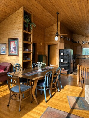A cozy cabin interior with a dining area, kitchen, and a living room with a sofa and chairs. - 30% OFF Members. Riverfront. Lake Of the Woods 2mi. Pets Free (Warroad)