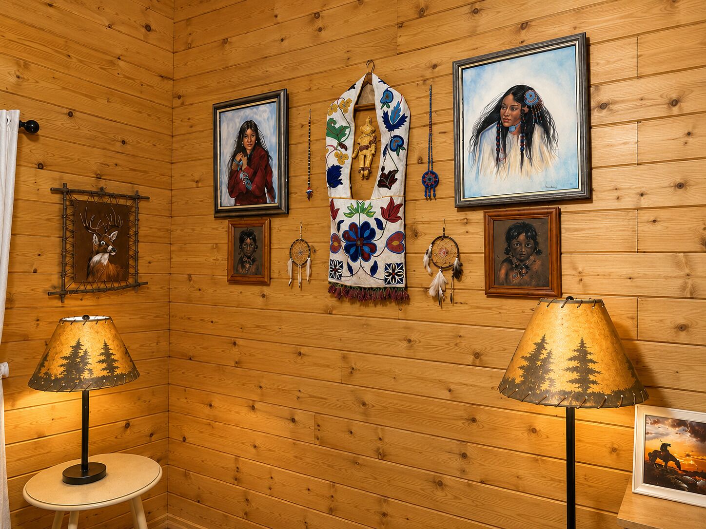 A room with wooden walls, framed artwork, a central woven blanket, and two lamps.