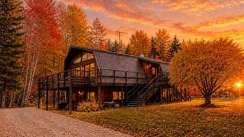 A cabin with a wooden exterior, a balcony, and a staircase leading to the upper level.