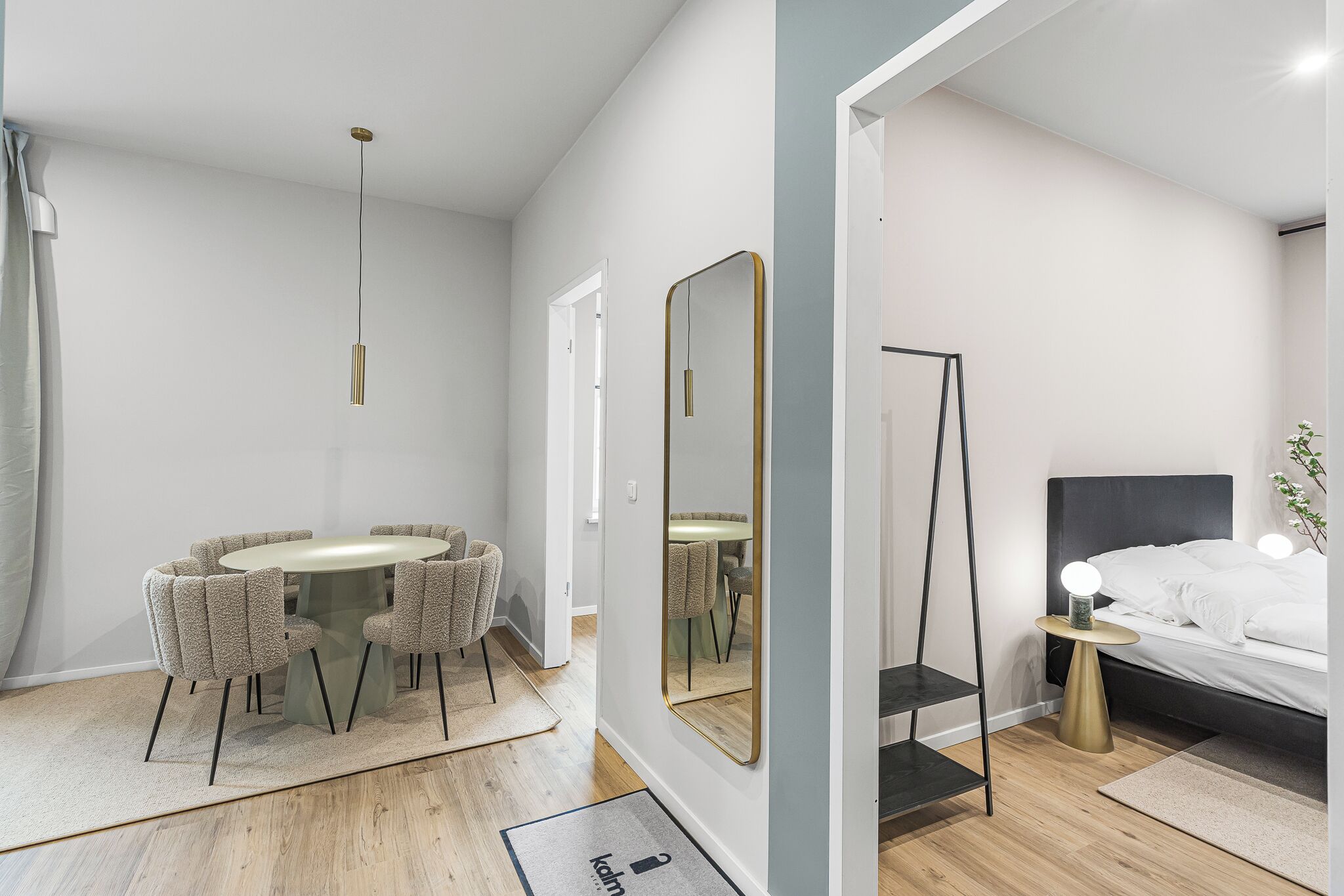 A modern bedroom with a bed, bedside table, and a mirror.