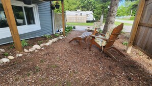 Une terrasse en bois avec deux chaises en bois et un pot de fleurs suspendu.