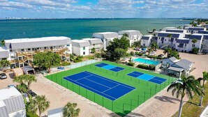 A coastal hotel with multiple tennis courts, a pool, and a view of the ocean. - Mariner Pointe #1021 – Sanibel Waterfront! (Sanibel)
