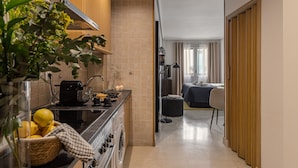 Une cuisine compacte équipée d’une cuisinière, d’un évier et d’un petit coin repas. On peut apercevoir un lave-linge dans un coin.