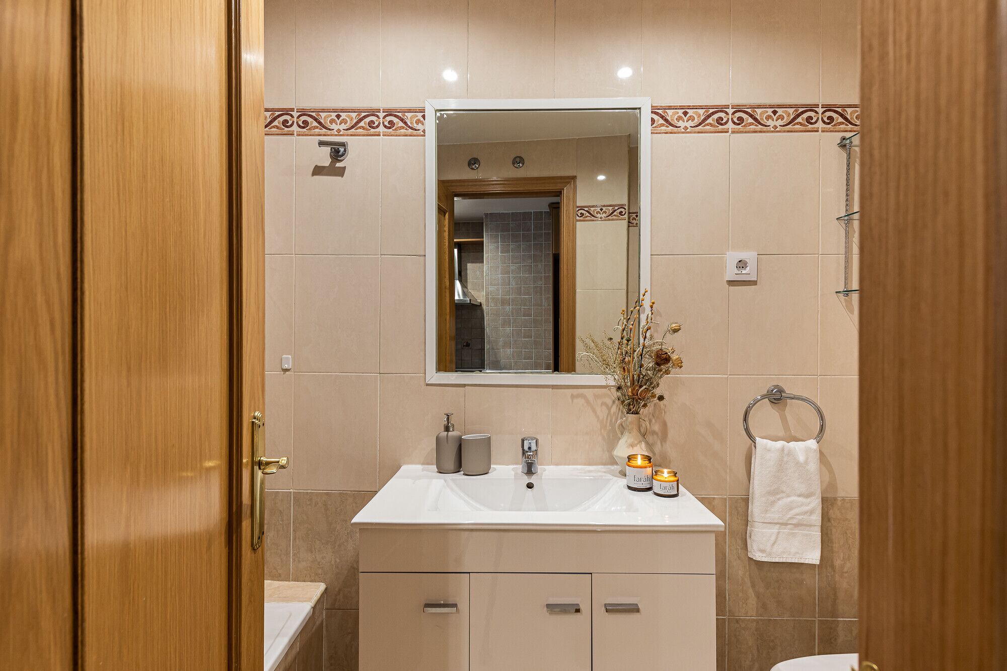 Un baño moderno con lavamanos, espejo y toallero.