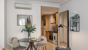 Een ruimtelijke woonruimte met een eethoek, kitchenette en een klein zithoekje.