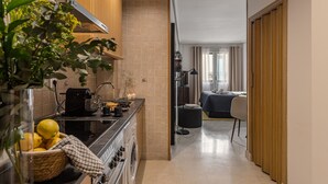 Een compacte keuken met een kookplaat, spoelbak en een klein eethoekje. Een wasmachine is in de hoek zichtbaar.