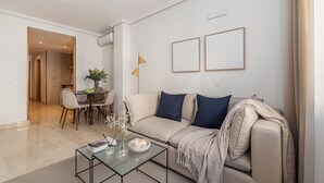 A living room with a sofa, coffee table, and a dining area with chairs and a table. - Waou Gran Via Apartment II - Corta Duració (Madrid)