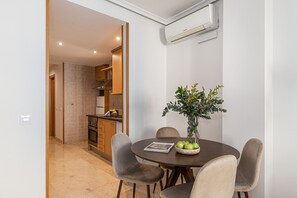 Un coin repas avec une table ronde, quatre chaises, un vase avec des fleurs et un magazine.
