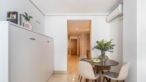 Eine moderne Küche mit Essbereich, ausgestattet mit einem weißen Schrank, einem runden Tisch mit Stühlen und einer Vase mit Blumen.