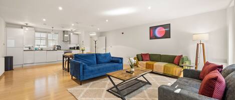 A modern living space with a kitchen, two sofas, a coffee table, and a floor lamp.