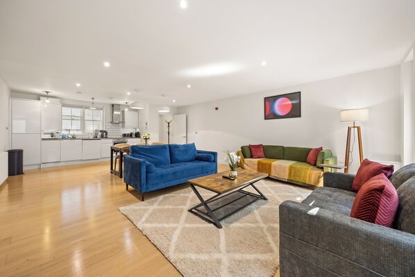 Ein moderner Wohnraum mit einer Küche, zwei Sofas, einem Couchtisch und einer Stehlampe.