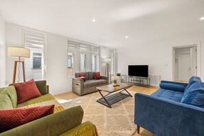 Ein modernes Wohnzimmer mit einer Sofagarnitur, einem Couchtisch und einem Fernseher.